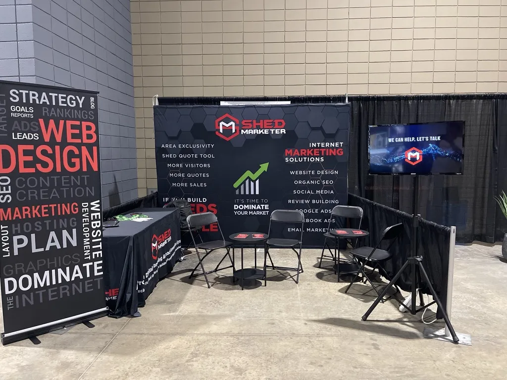 The Shed Marketer trade-show booth, with the marketing-services backdrop and stacks of the Selling Sheds Online book on the table